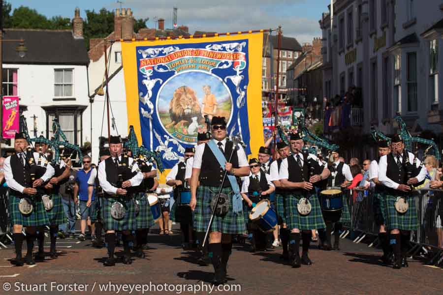 A marching pipe band participates the parade of banners past the County Hotel in Durham.