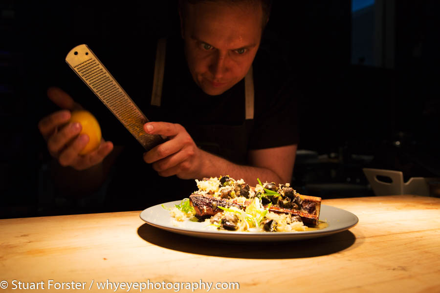 Chef Darren MacLean at Shokunin, Calgary grating zest into a plate of Japanese-influenced cuisine.