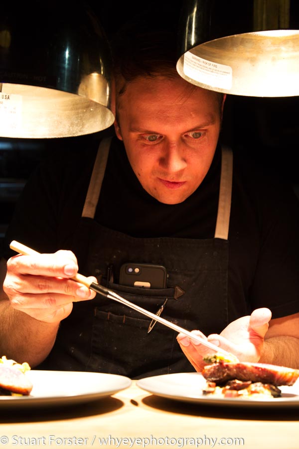 Darren MacLean ensuring every leaf and petal is properly placed while plating food in the kitchen of Shokunin in Calgary.