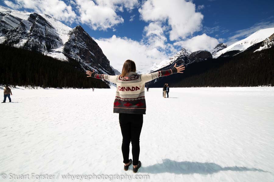 Woman in a Canada cardigan on the frozen surface of Lake Louise in Alberta, which can be visited while riding the Rocky Mountaineer luxury train.