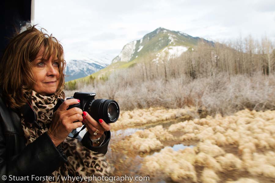 A woman photographs from the Rocky Mountaineer in Alberta.