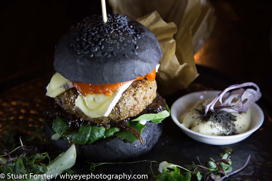 Lamb burger served with in a black bread bun with a slice of French cheese at a restaurant in Riga, Latvia