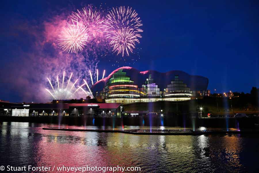 Firework display during the opening ceremony of the Great Exhibition of the North. Rockets burst into the sky above the Sage Gateshead.