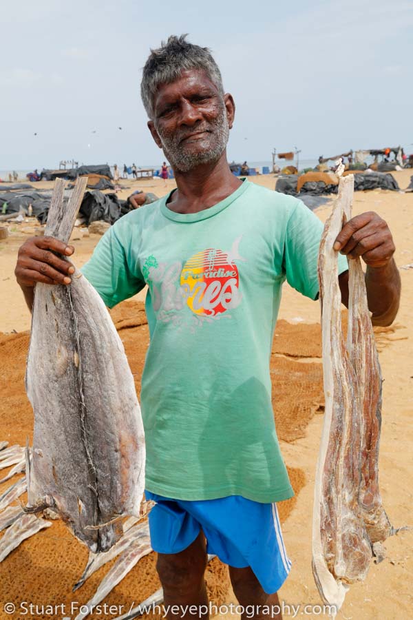 A local man shows off some of the salted fish that have been dried on the beach in Negombo,