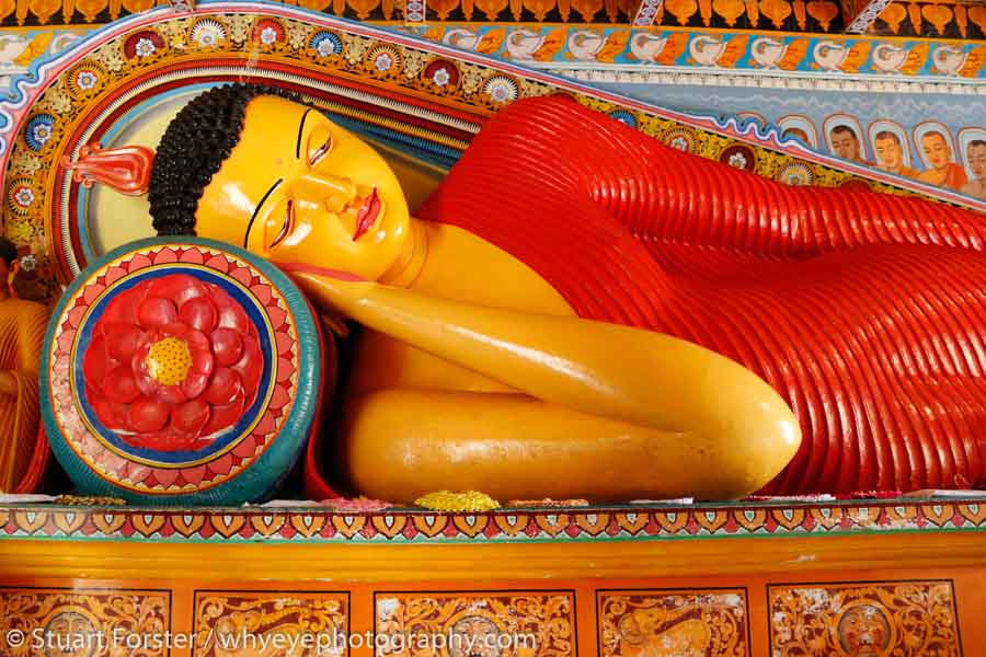 A colourfully painted statue of Buddha reclining at the Isurumuniya Temple near Anuradhapura, one of Sri Lanka's UNESCO World Heritage Sites.