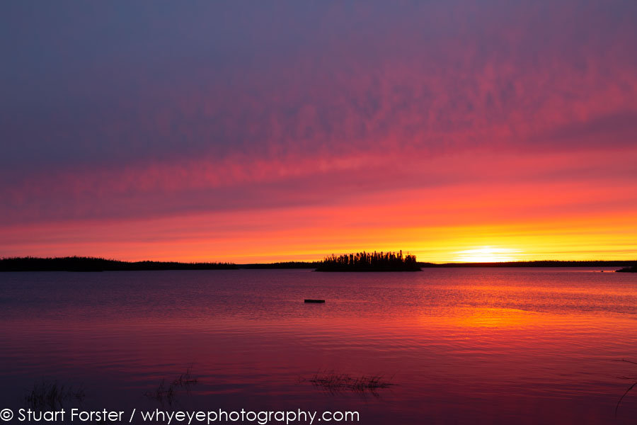 A golden sunrise over the placid water of Egenolf Lake such landscapes reward photography in northern Manitoba, Canada.