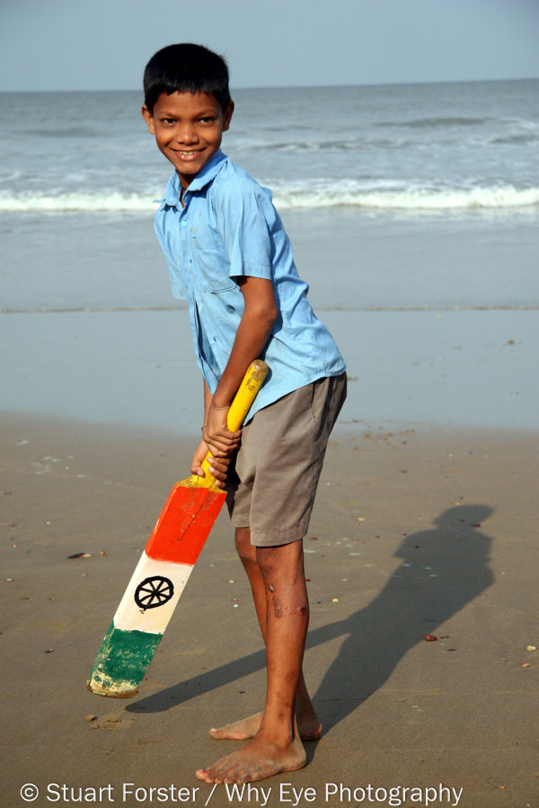If your horizon isn't straight why not retake the photograph? This boy holding an cricket bat with an Indian flag is on a beach in Karnataka, India.