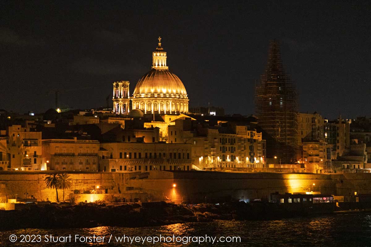 The Valletta waterfront at night with the illuminated landmark of the cupola of the Basilica of Our Lady of Mount Carmel dominating the skyline of the Maltese capital.